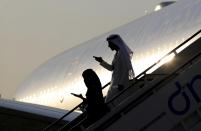 People climb down the stairs of a plane, on the opening day of Dubai Airshow, in the United Arab Emirates, Sunday, Nov. 17, 2019. The biennial airshow has opened as major Gulf airlines reign back big-ticket purchases after a staggering $140 billion in new orders were announced at the 2013 show before global oil prices collapsed. (AP Photo/Kamran Jebreili)