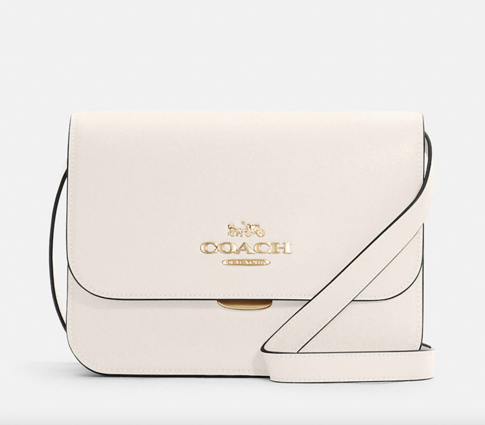 Brynn Flap Crossbody in white leather with coach in gold print (Photo via Coach Outlet)