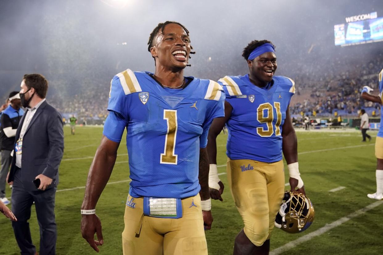 UCLA quarterback Dorian Thompson-Robinson and defensive lineman Otito Ogbonnia walk off the field.