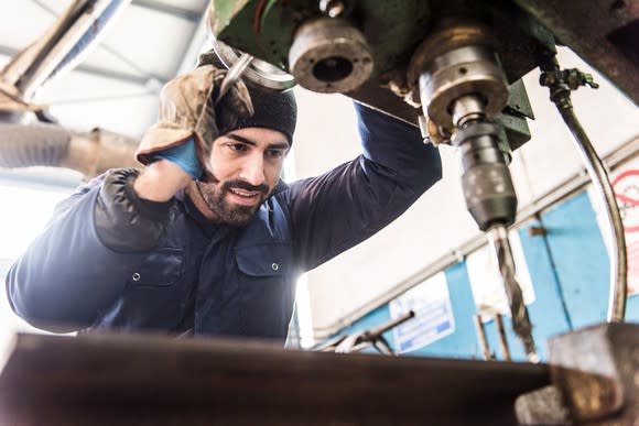 A factory worker at a drill press.