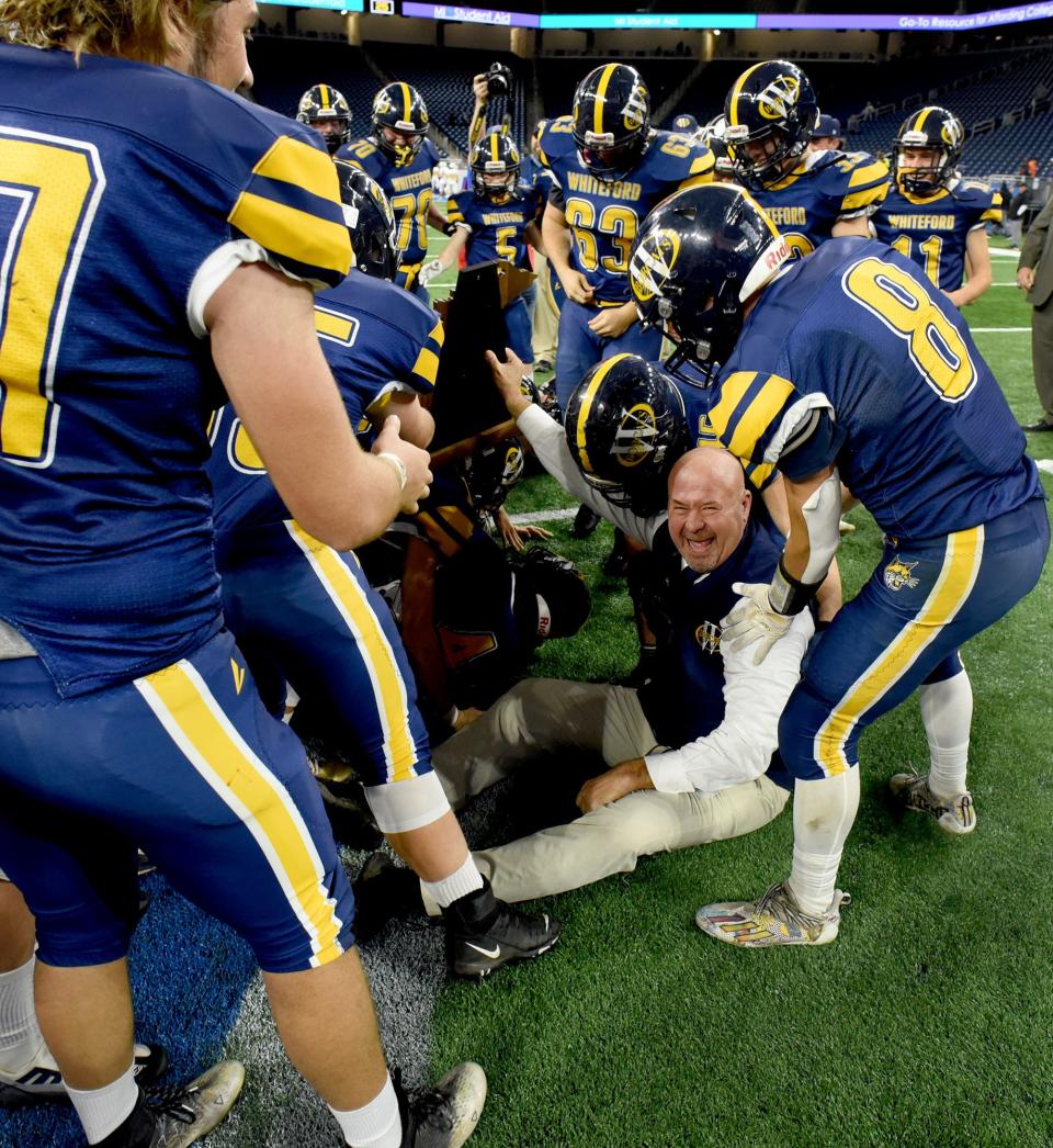 Whiteford coach Todd Thieken laughs after stumbling while presenting the Division 8 state championship trophy to his team Friday at Ford Field.