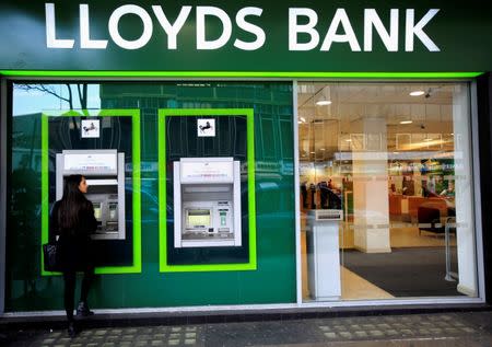 FILE PHOTO: A woman uses a cash machine at a Lloyds Bank branch in central London, Britain February 25, 2016. REUTERS/Paul Hackett/File Photo