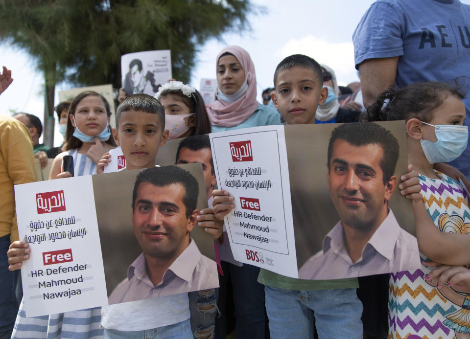 Aws, 7, left, and Amr, 9, hold posters with a picture of their father, Mahmoud Nawajaa, a leading coordinator of the Palestinian-led boycott movement against Israel, BDS, during a protest calling for the EU to press for his release, in front of the German Representative Office, in the West Bank city of Ramallah, Tuesday, Aug. 11, 2020. The activist was arrested on July 30, remains in Israeli custody and has not been charged. Israel says the arrest is not connected to his boycott activities, and that he is is suspected of unspecified “security offenses," but boycott activists accuse Israel of fabricating the case in order to justify the arrest. (AP Photo/Nasser Nasser)