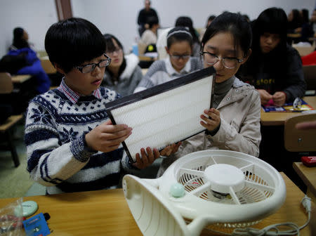 Students hold a HEPA filter as they prepare to put it on a fan at a workshop to learn how to make the DIY air purifier at a college in Beijing October 23, 2014. Smart Air, a company which invented the DIY air filter, said that their DIY device, which combines a basic household fan with a simple HEPA filter can reduce particulate air pollution indoors at low-cost. REUTERS/Kim Kyung-Hoon