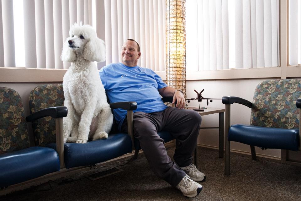 Paul Turner, manager of the Maury County Airport, sits with his dog Bella in the airport's lounge in Mount Pleasant, Tenn. on Wednesday, June 14, 2023. Customers love to be greeted by Bella he says.