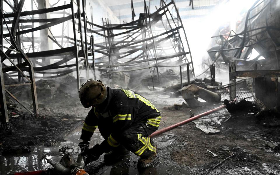 A Ukrainian firefighter works to put out a blaze at a shopping mall in Kherson - Genya SAVILOV / AFP
