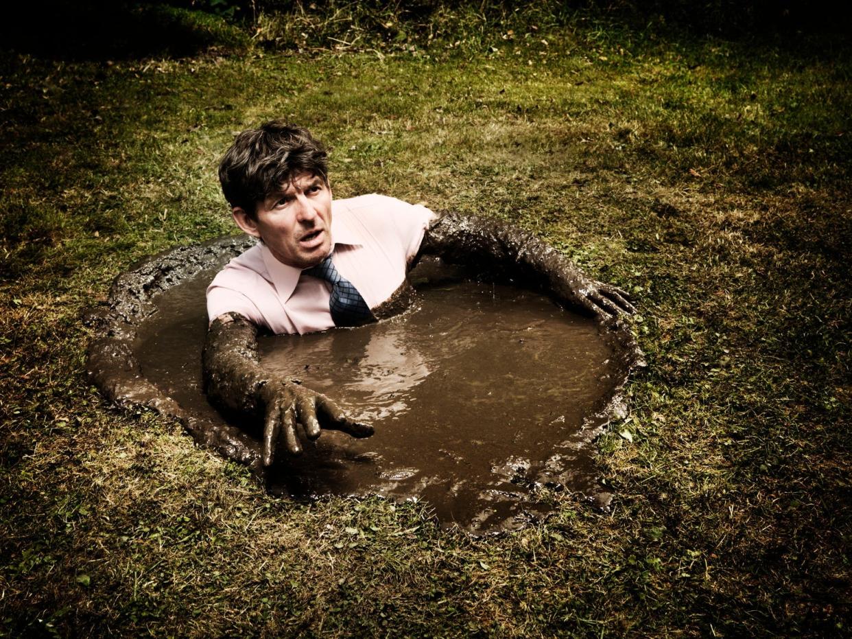 A man stuck in quicksand up to his chest.