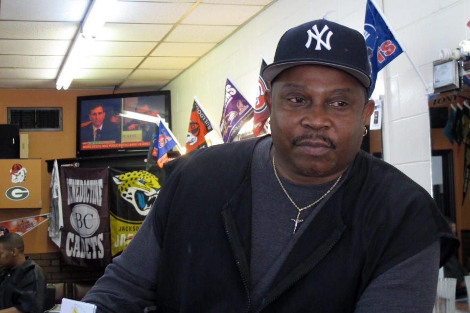 Anthony Harris sits inside his barber shop, Holmes II, in Savannah, Ga., while a live broadcast of the congressional impeachment hearing plays on television, Wednesday, Nov. 13, 2019. Harris said he believes President Donald Trump should be removed from office, but he's tired of the president's daily domination of the news. He said: "Personally, at this time of day I'd rather watch Andy Griffith." (AP Photo/Russ Bynum)