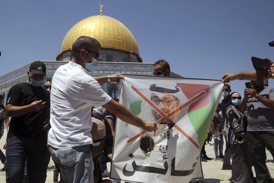 Palestinian protesters burn a banner showing Abu Dhabi Crown Prince Mohamed bin Zayed al-Nahyan during a protest against the United Arab Emirates' deal with Israel near the Dome of the Rock Mosque in the Al Aqsa Mosque compound in Jerusalem's old city, Friday, Aug. 14, 2020. (AP Photo/Mahmoud Illean)