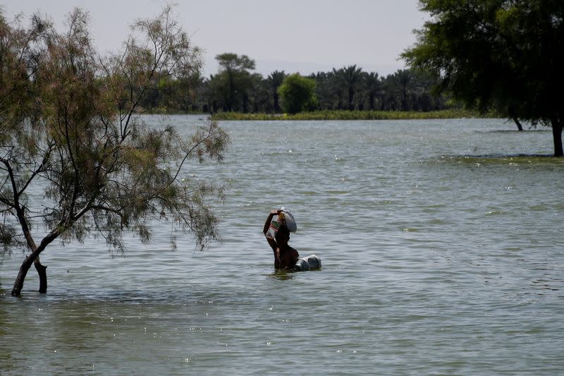 A flood victim wades through flood water, following rains and floods during the monsoon season in Bajara village, Sehwan