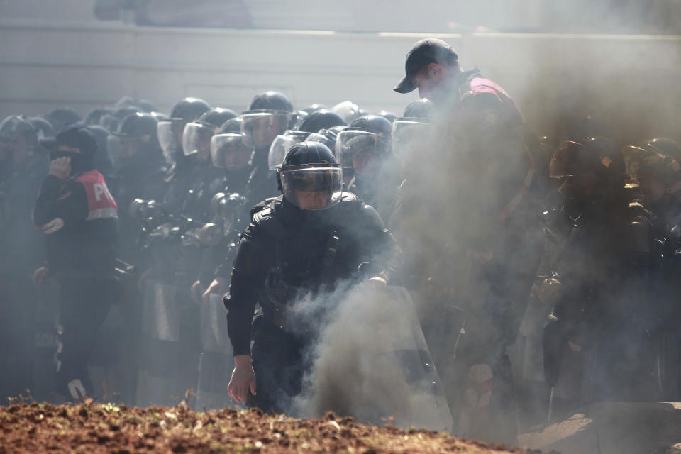 Riot polices are seen through the smoke as they stand guard during an anti-government rally in Tirana, Albania, Thursday, March 21, 2019. Thousand opposition protesters have gathered in front of Albania's parliament building calling for the government's resignation and an early election. Rally is part of the center-right Democratic Party-led opposition's protests over the last month accusing the leftist Socialist Party government of Prime Minister Edi Rama of being corrupt and linked to organized crime. (AP Photo/ Hektor Pustina)