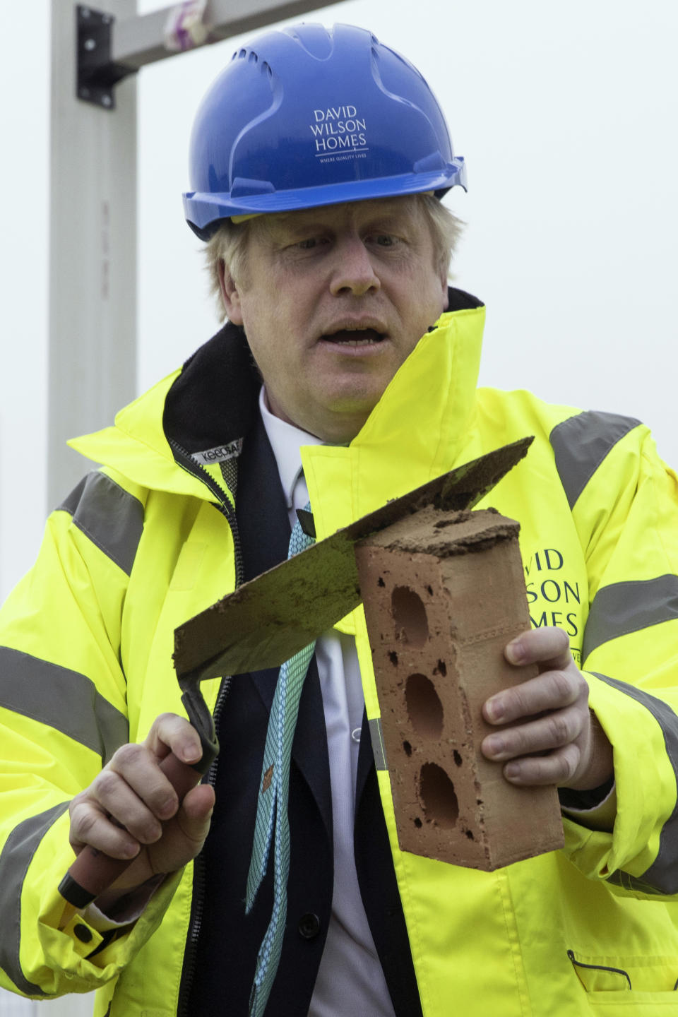 Britain's Prime Minister Boris Johnson lays a brick during a visit to the Barratt Homes - Willow Grove housing development in Bedford, England, Thursday, Nov. 21, 2019. Britain’s main opposition Labour Party promised Thursday to radically expand public spending and state ownership if it wins the Dec. 12 election, trying to close an opinion-poll gap with the governing Conservatives (Dan Kitwood/Pool photo via AP)