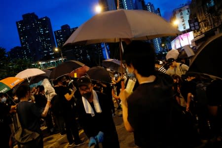 Protesters hold umbrellas to protect themselves from being pepper-sprayed after a march at Sheung Shui, Hong Kong