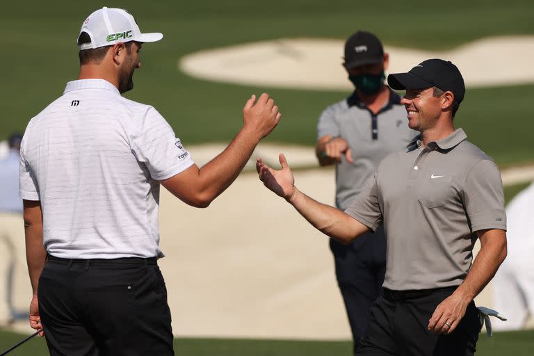 Rory McIlroy (derecha), saludando al español Jon Rahm; el norirlandés va por el Major que le falta