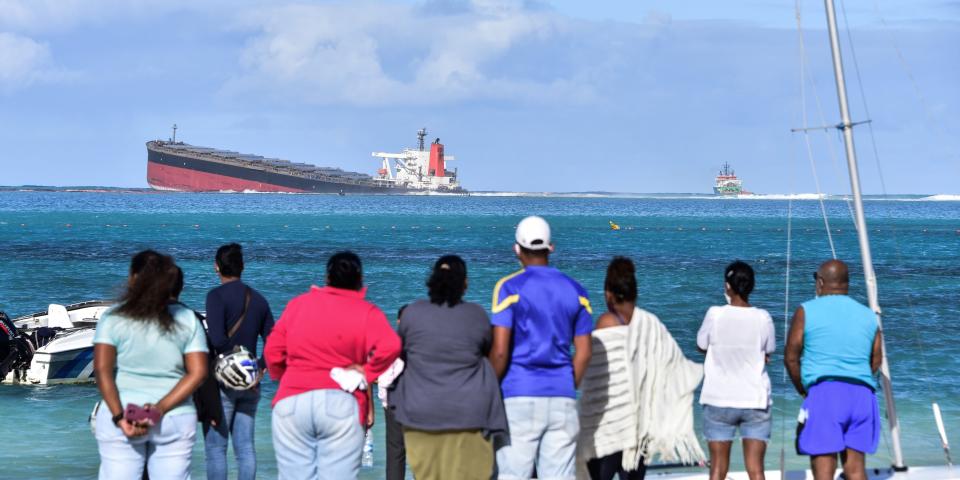 ystanders look at MV Wakashio bulk carrier that had run aground and from which oil is leaking near Blue Bay Marine Park in south-east Mauritius on August 6, 2020.