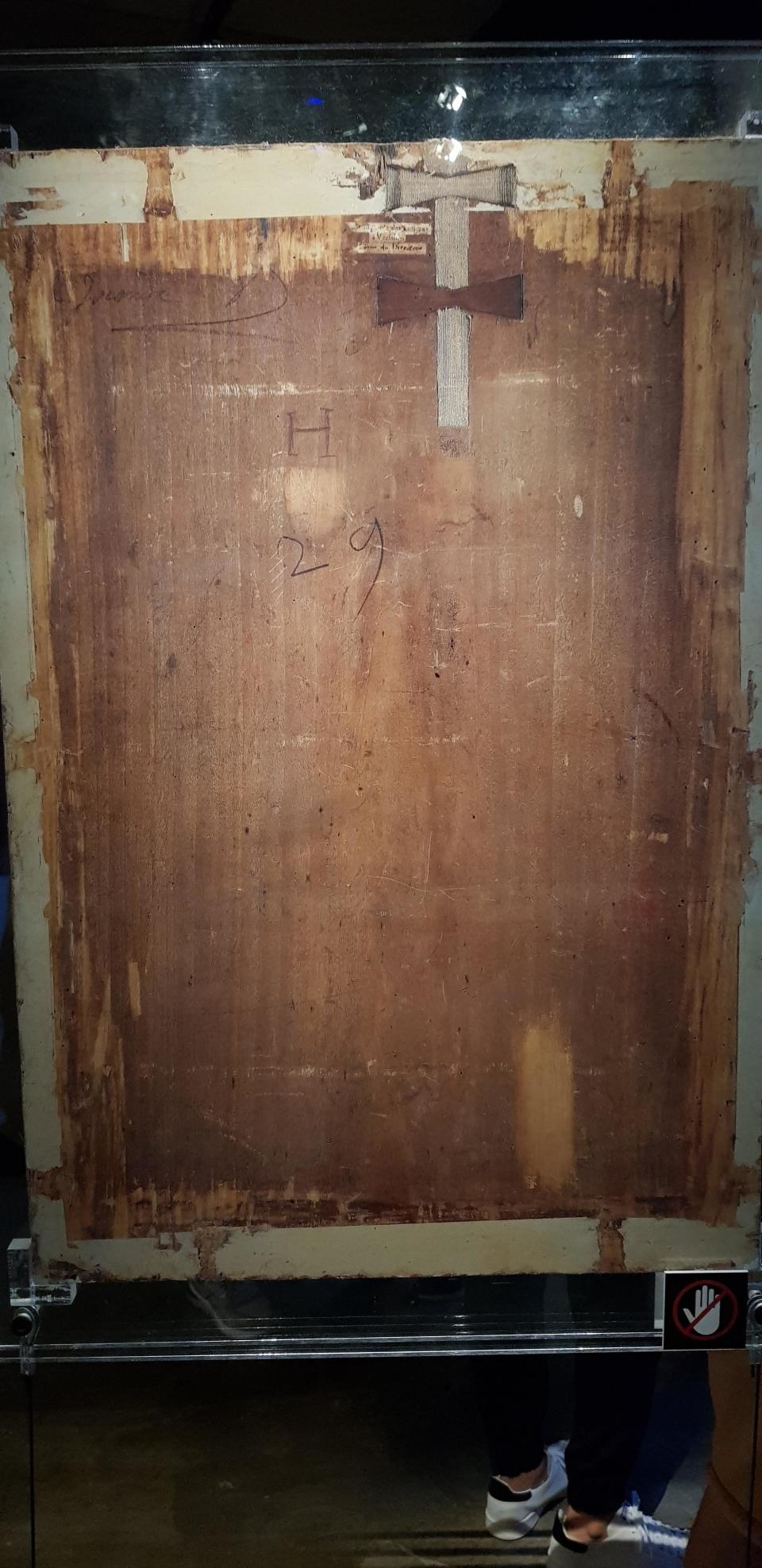 A nondescript back of a wooden canvas with "H" and "29" written on it