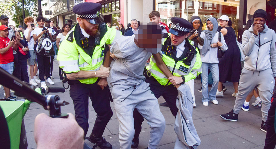 Police lead a man away as officers made nine arrests in total. (Shutterstock)