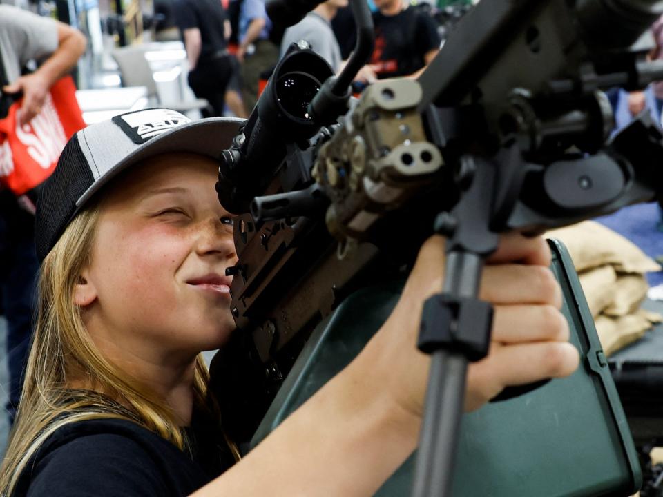 A 14-year-old from Illinois holds a machine gun at the National Rifle Association annual convention.