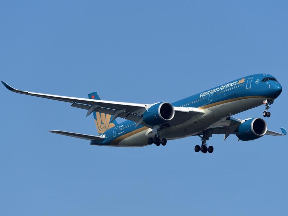 A Vietnam Airlines Airbus A350-900 aircraft flying in a clear blue sky.