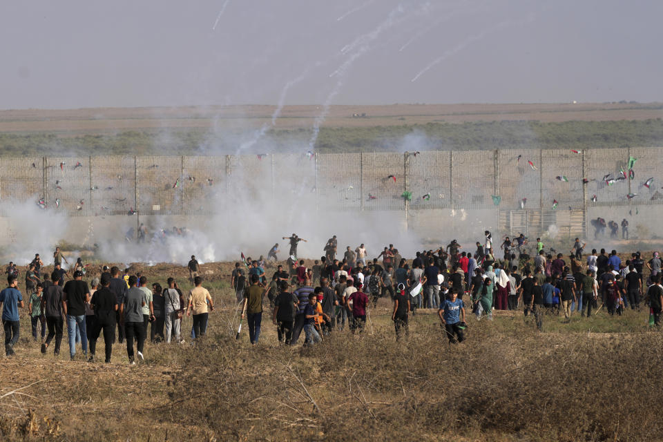 Palestinian protesters run to cover from tear gas during clashes with Israeli troops, along the frontier with Israel, east of Gaza City, Monday, Aug. 21, 2023. Hundreds of Palestinians protested near the border fence with Israel. The Gaza Health Ministry said at least eight people were wounded by Israeli fire and tear gas. (AP Photo/Adel Hana)