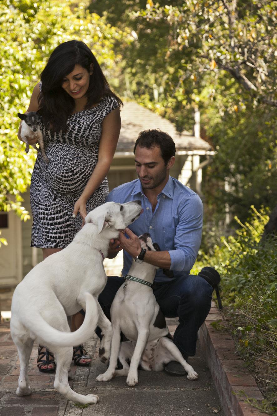 In this photo taken Friday, May 11, 2012, husband and wife entrepreneurs Aaron and Karine Hirschhorn pose with hosted dogs at a home in Los Angeles. Instead of putting pets in kennels, Dog Vacay brings together dog lovers with casual and professional dog sitters to provide an affordable experience for pets. (AP Photo/Damian Dovarganes)
