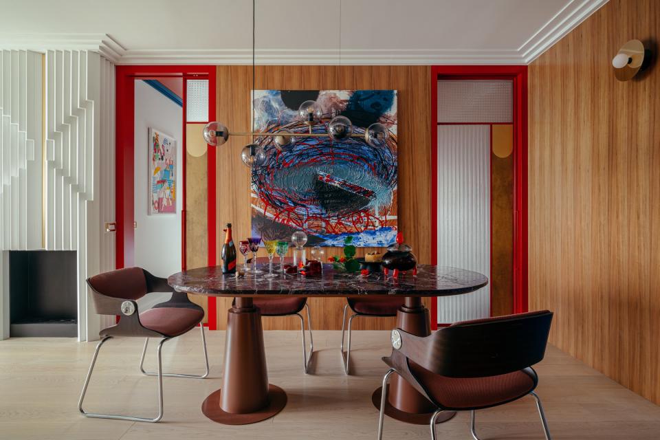 The crown jewel of the dining room is the elliptical dining table with a Rosso Lepanto marble top, which Magdalena tailored to the shape and proportions of the room. Behind it hangs an eye-popping painting by Eugeniusz Minciel, flanked by full-height crimson doors by Baranska Design that slide open like Mondrian stage screens. Bolia’s Orb pendant haloes the setting, while Disc and Sphere wall lights by Atelier Areti give the walls a glow-up. The chairs are Eugen Schmidt originals.