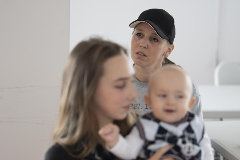 Kateryna Kyreieva, background, the mother of Vlada Yushchenko, a 19-year-old Ukrainian refugee speaks, during an interview with The Associated Press in Brasov, Romania, Thursday, Feb. 2, 2023. Yushchenko was still in her teens and nearly three months pregnant when she hugged her husband at the border, turned away and walked into Moldova. Now she’s in Romania, one of the millions of Ukrainians forced to flee Russia’s invasion of their country. Her baby, Daniel, was born there eight months ago and still hasn’t met his father Yaroslav, who is 21 and, like most men of fighting age, prohibited from leaving Ukraine. (AP Photo/Vadim Ghirda)