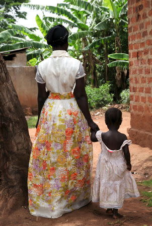 A three-year-old girl who was offered for international adoption without her family's knowledge walks with the grandmother near their home in rural Uganda, April 14, 2015. REUTERS/Katy Migiro