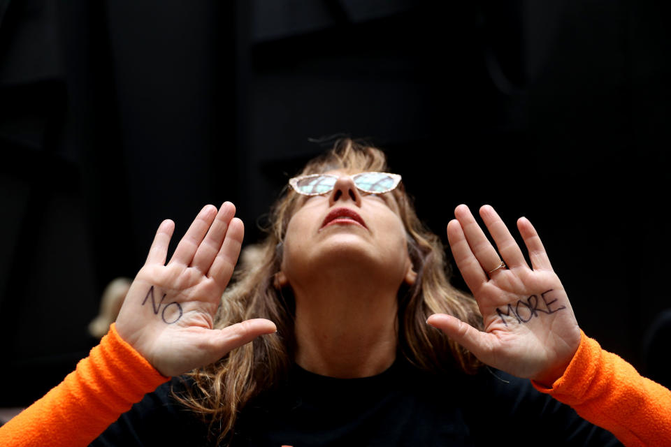 A protester displays a note on her hand that reads 'No More' while demonstrating.