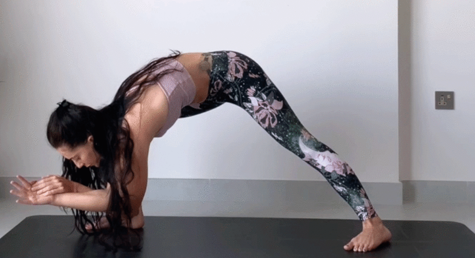 Woman standing on a yoga mat practicing Humble Warrior