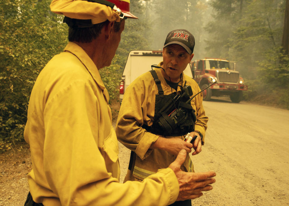 Firefighter Paul Schlange, left, confers while fighting the Caldor Fire on Hazel Valley Road east of Riverton, Calif., on Thursday, Aug. 19, 2021. (AP Photo/Ethan Swope)