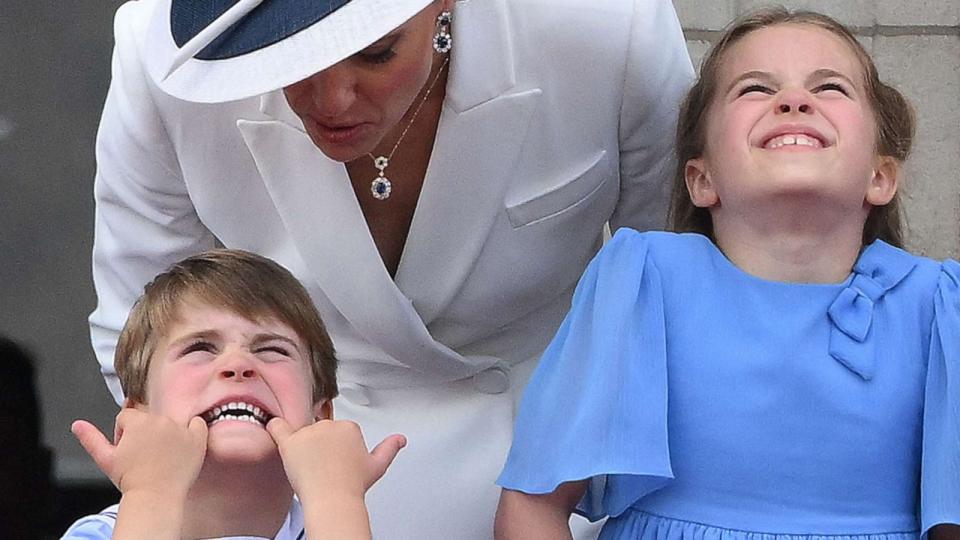 PHOTO: Catherine, Duchess of Cambridge talks to Prince Louis who is pulling a funny face, as they stand with Princess Charlotte of Cambridge to watch a special flypast from Buckingham Palace balcony in London on June 2, 2022. (Daniel Leal/AFP via Getty Images)