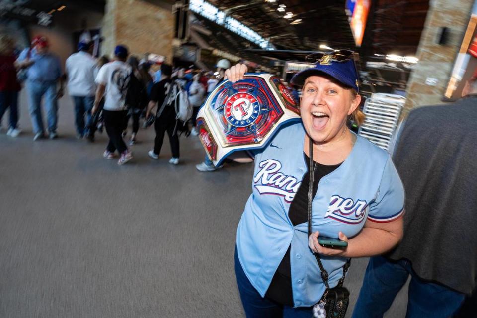 Roanoke resident Jenifer Watson cheers as she holds her custom-made Texas Rangers championship belt for the 2024 season opener between the Rangers and the Chicago Cubs at Globe Life Field in Arlington on Thursday, March 28, 2024. Chris Torres/ctorres@star-telegram.com