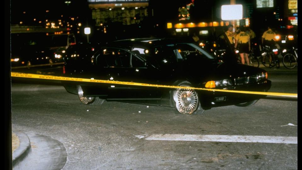 black car in which rapper tupac shakur was fatally shot by unknown driveby assassins as he was riding w friend death row records pres marion suge knight, who survived shooting, behind police tape at crime scene