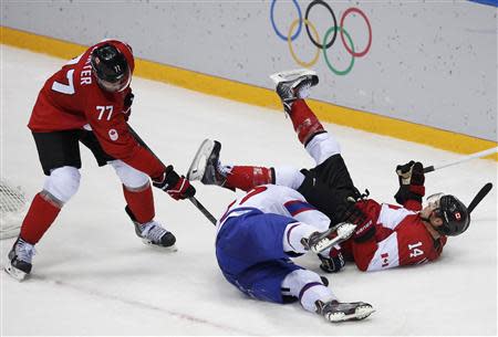 Canada's Chris Kunitz (14) falls over Norway's Alexander Bonsaksen as Canada's Jeff Carter attempts to dig out the puck during the third period of their men's preliminary round ice hockey game at the 2014 Sochi Winter Olympic Games, February 13, 2014. REUTERS/Grigory Dukor