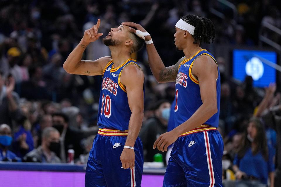 Golden State Warriors guard Stephen Curry (30) points to the sky as he gets a pat on the head from Damion Lee (1) after making a 3-point shot against the Los Angeles Clippers during the first half of an NBA basketball game in San Francisco, Thursday, Oct. 21, 2021. (AP Photo/Tony Avelar)