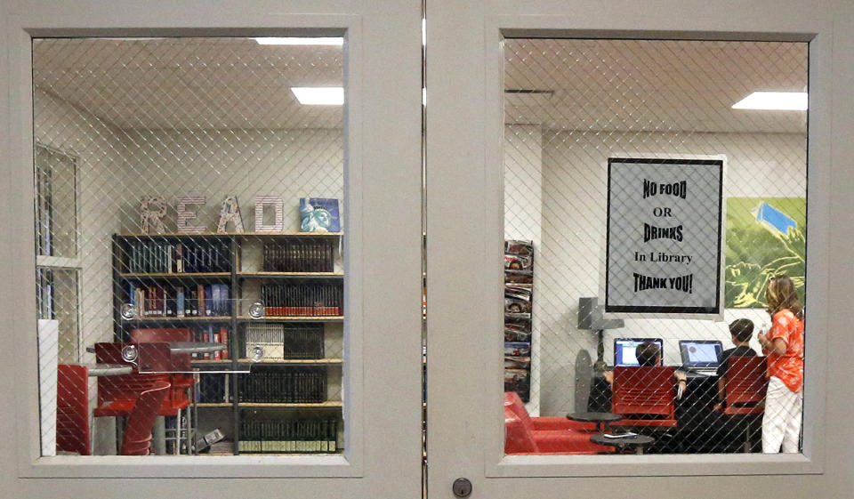 In this May 8, 2019, photo, the Stidham family does homework in the library of the East Webster High School, in Maben, Miss. The Stidhams are unable to get internet at their home in the county, so they take advantage of the internet in the school's library to work on their homework. (AP Photo/Rogelio V. Solis)