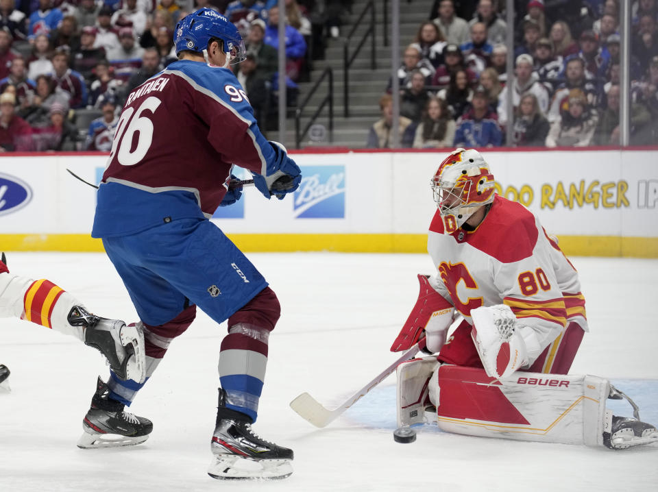 Colorado Avalanche right wing Mikko Rantanen, left, redirects the puck at Calgary Flames goaltender Dan Vladar, right, in the first period of an NHL hockey game Saturday, Nov. 25, 2023, in Denver. (AP Photo/David Zalubowski)