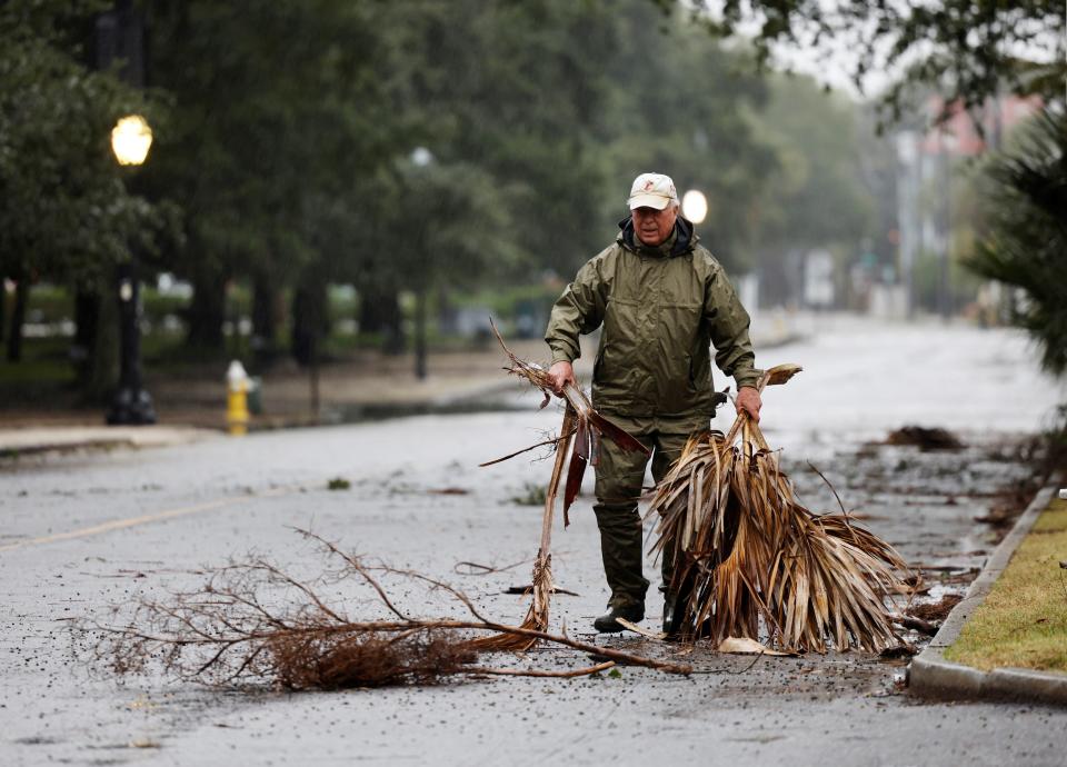 A man clears branches from a road in Charleston to keep the gutters clear when Hurricane Ian arrives on Friday (REUTERS)