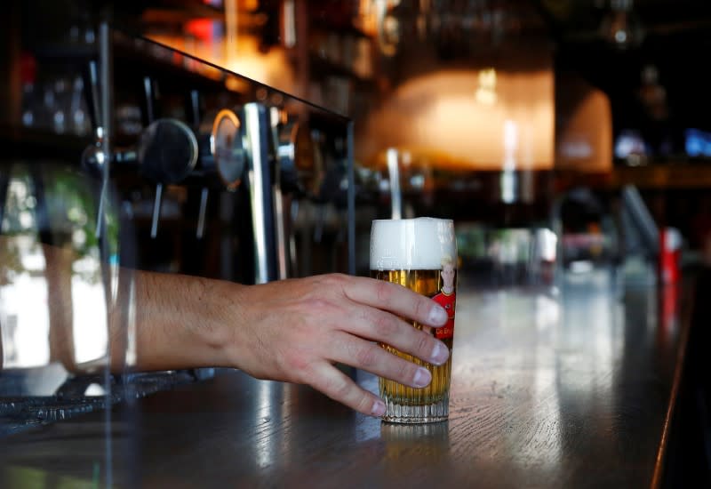 Bar owner tests a protective plexiglass screen installed on the counter, in Brussels