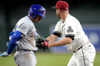 Chicago Cubs' Ian Happ, left, is tagged out by Arizona Diamondbacks pitcher Merrill Kelly on a ground out during the fifth inning of a baseball game, Monday, April 15, 2024, in Phoenix. (AP Photo/Matt York)