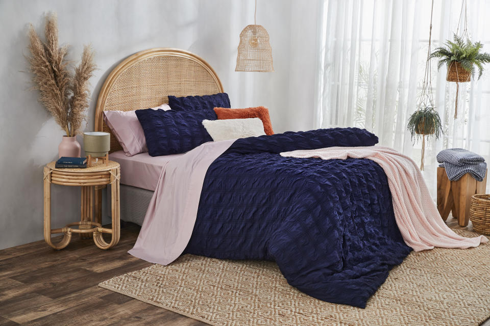 a bed made up with quilt cover, throws and cushions