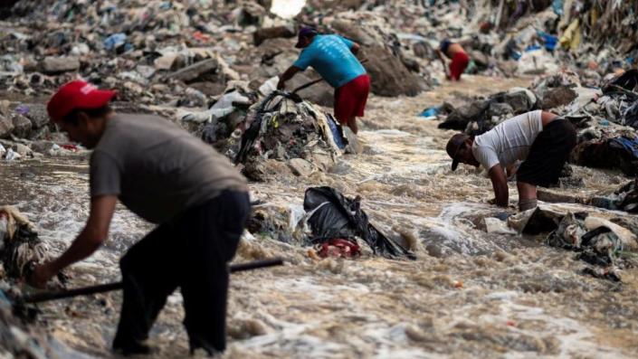 Hombres excavan en busca de chatarra en las aguas contaminadas del río Las Vacas