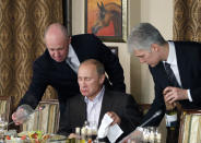 Yevgeny Prigozhin, left, serves food to then-Prime Minister Vladimir Putin, center, during dinner at Prigozhin's restaurant outside Moscow, Russia, Friday, Nov. 11, 2011. Prigozhin later became head of the Wagner private military company, which has sent its forces to Syria, Ukraine and several African countries. (AP Photo/Misha Japaridze, Pool, File)