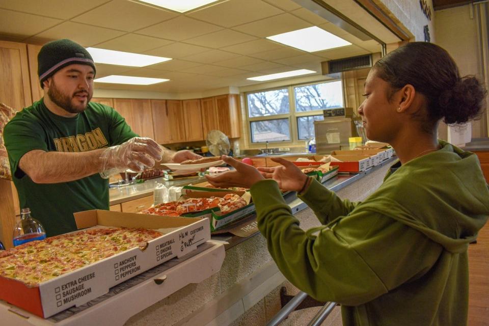 Noah Brown serves pizza to Saebra Cooks, 12, of Fremont during Pizza Party for the Pantry at St. Paul Lutheran Church on March 18.