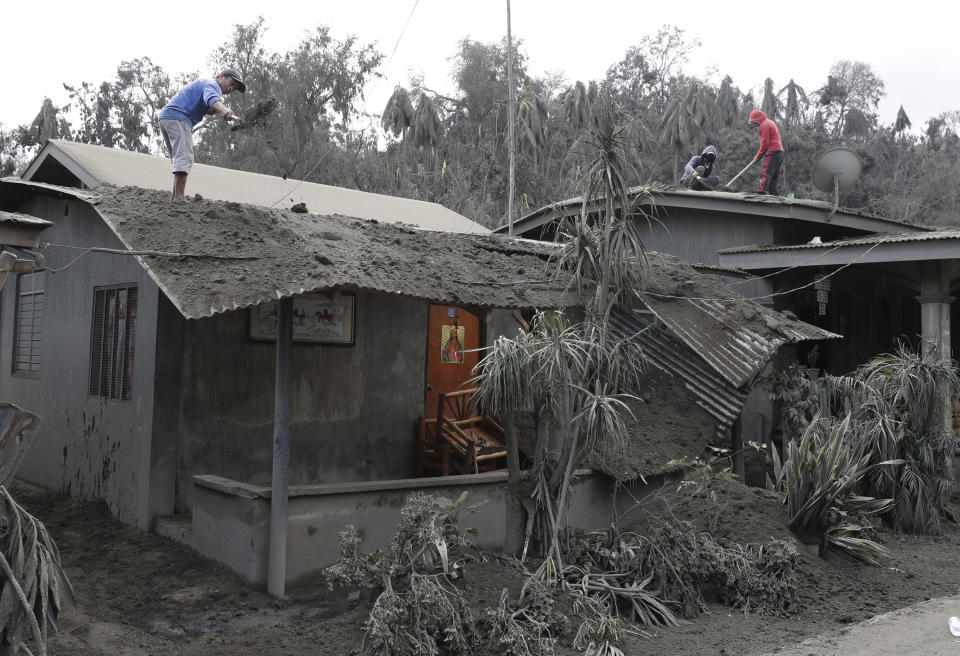 Tres lugareños limpian las cenizas del techo de una casa en Laurel, al sur de las Filipinas, tras la erupción de un volcán el 14 de enero del 2020. (AP Photo/Aaron Favila)