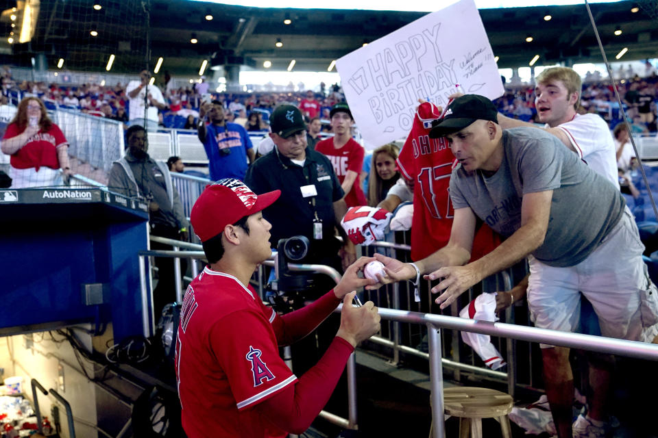 A fan holds a happy birthday sign as Los Angeles Angels' Shohei Ohtani signs autographs before the team's baseball game against the Miami Marlins, Tuesday, July 5, 2022, in Miami. Ohtani turned 28 on Tuesday. (AP Photo/Lynne Sladky)