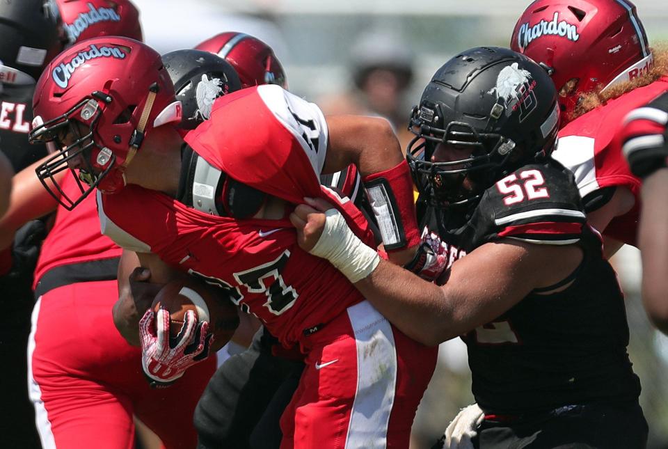 Buchtel defensive lineman Davian Greenlee, right, pulls down Chardon running back Daniel Pettyjohn during the first half of a high school football game, Saturday, Aug. 28, 2021, in Akron, Ohio. [Jeff Lange/Beacon Journal]