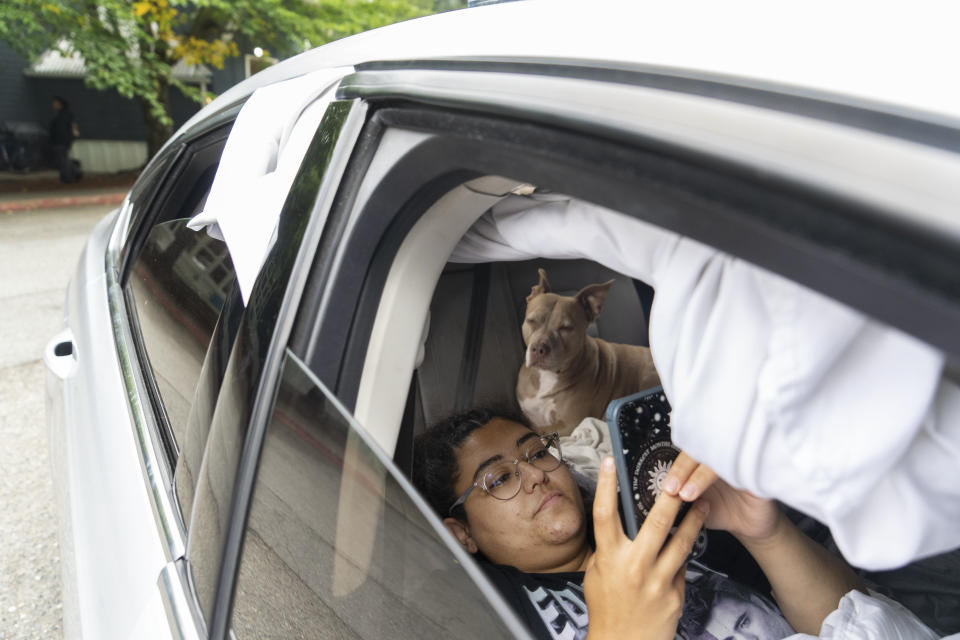 Cierra Audet y su perro, Coda, dentro del automóvil en el que duermen con la madre de Cierra, Chrystal Audet, en un estacionamiento de SafePark afuera de una Iglesia Metodista Unida en Kirkland, Washington, el 28 de agosto de 2023. La familia se encuentra entre una creciente cohorte de trabajadores estadounidenses que viven en sus automóviles. (Ruth Fremson/Los New York Times)