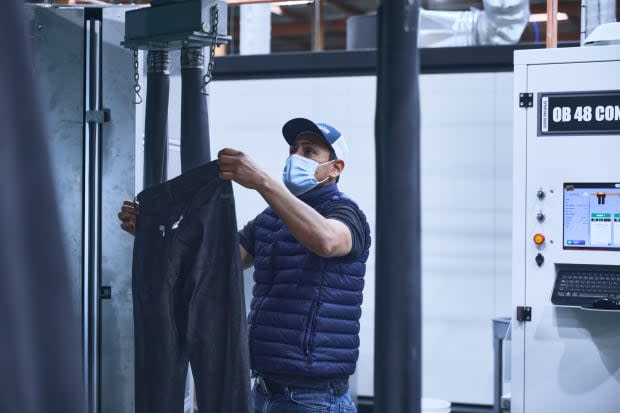 An employee places raw jeans on an automated machine.<p>Photo: Courtesy of Saitex</p>